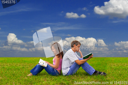 Image of two teenagers studying outdoors on grass