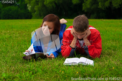 Image of two teenagers studying outdoors on grass