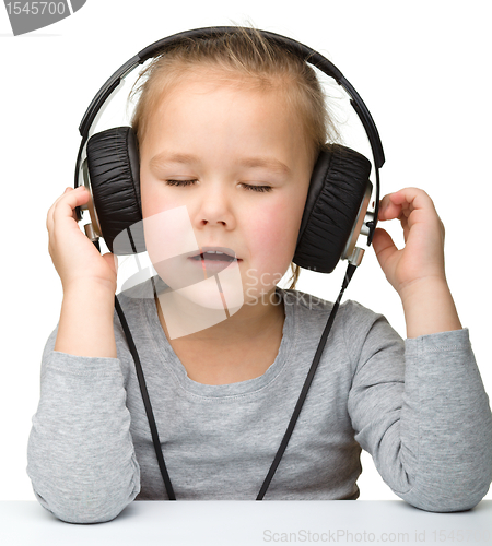 Image of Cute girl enjoying music using headphones