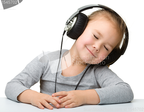 Image of Cute girl enjoying music using headphones