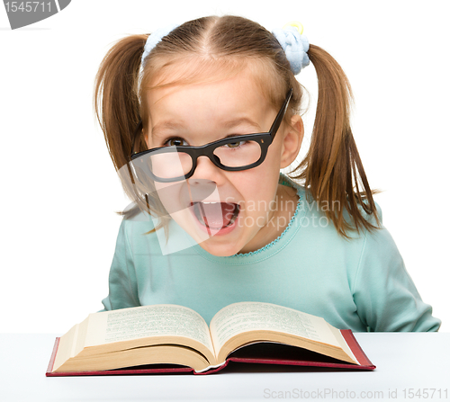 Image of Little girl reads a book while wearing glasses