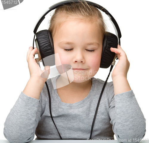 Image of Cute girl enjoying music using headphones