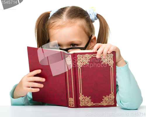 Image of Little girl is hiding behind a book