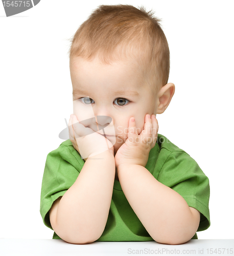 Image of Pensive little boy support his head with hands