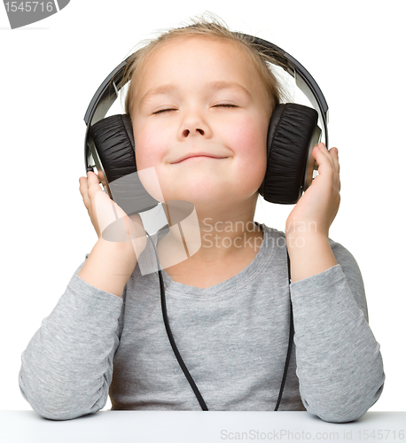 Image of Cute girl enjoying music using headphones