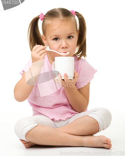 Image of Cute little girl is eating yogurt