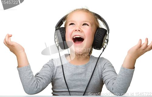 Image of Cute girl enjoying music using headphones