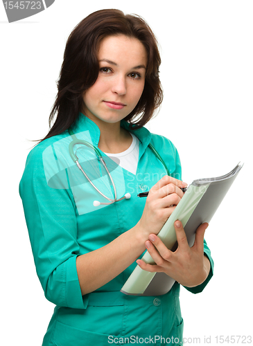 Image of Young attractive woman doctor is writing