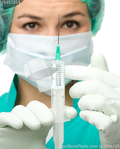 Image of Young nurse is preparing syringe for injection