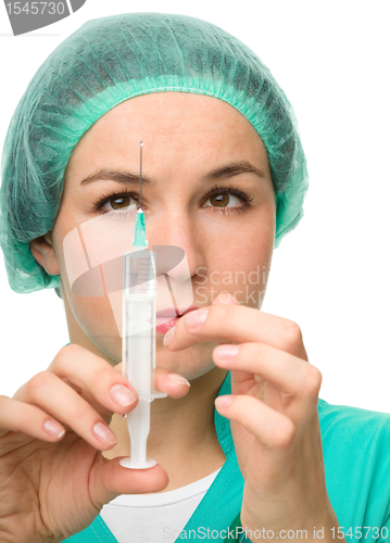 Image of Young nurse is preparing syringe for injection
