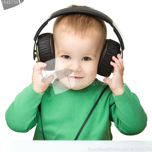 Image of Cute boy enjoying music using headphones