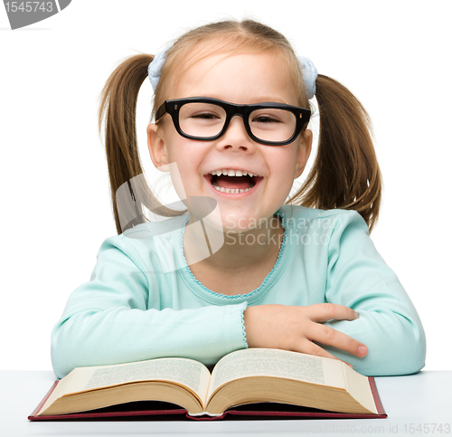 Image of Little girl reads a book while wearing glasses