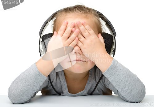 Image of Unhappy girl listening music using headphones