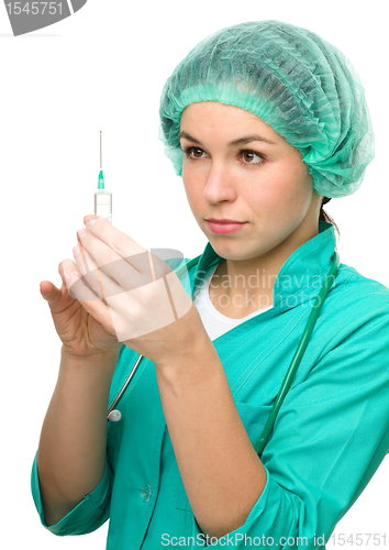 Image of Young nurse is preparing syringe for injection