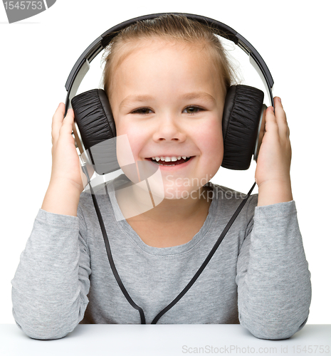Image of Cute girl enjoying music using headphones