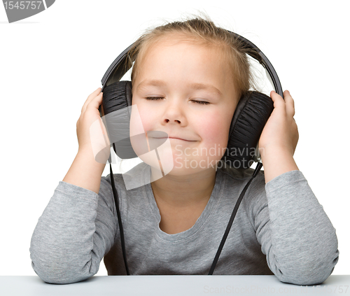 Image of Cute girl enjoying music using headphones