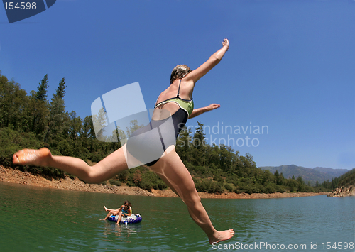 Image of Young woman jumping in the lake