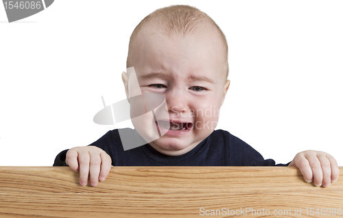 Image of crying young child holding wooden board