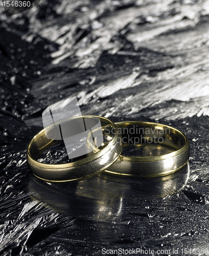 Image of two golden wedding rings on ice surface