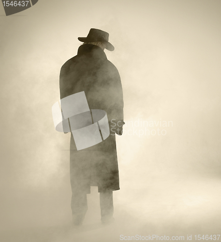 Image of Woman wearing trench coat and standing in fog