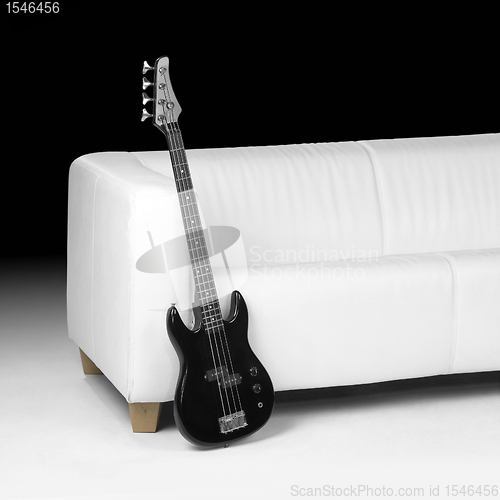 Image of black bass guitar and white couch