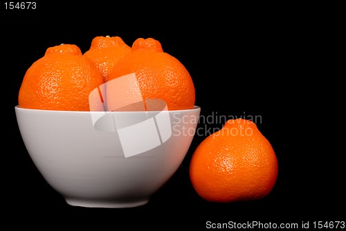 Image of Three minneola oranges in white bowl with one orange at side