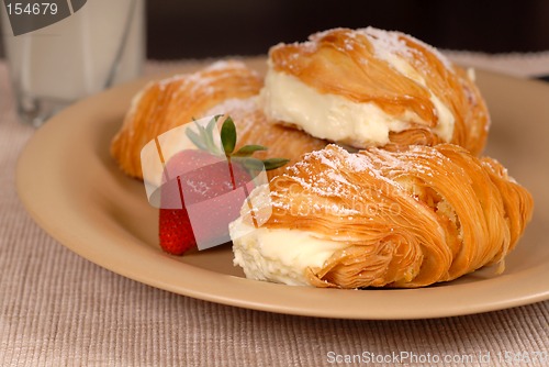 Image of Three sfogliatelle's with strawberry on tan plate
