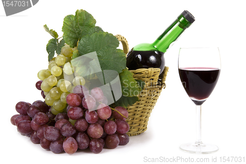 Image of white and red grape with leaves and bottle of wine in the basket