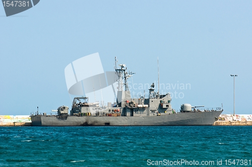 Image of Big battle ship in the dock against blue sky and mountains