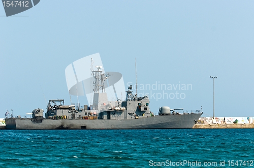 Image of Big battle ship in the dock against blue sky and mountains