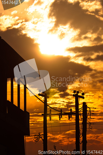 Image of Silhouette of a high voltage post and a house