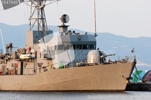 Image of Big battle ship in the dock against blue sky and mountains