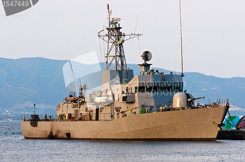 Image of Big battle ship in the dock against blue sky and mountains