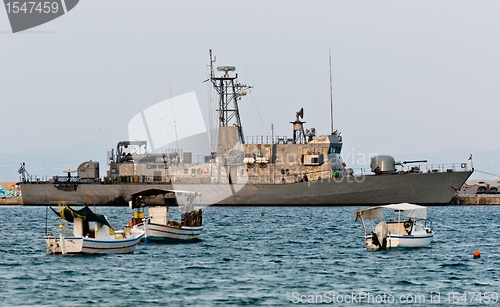 Image of Big battle ship in the dock against blue sky and mountains