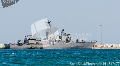 Image of Big battle ship in the dock against blue sky and mountains