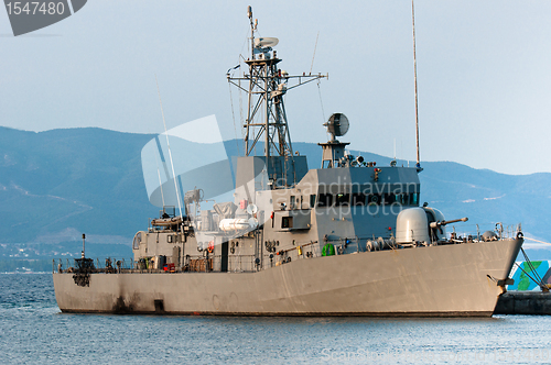Image of Big battle ship in the dock against blue sky and mountains