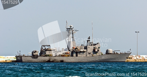 Image of Big battle ship in the dock against blue sky and mountains