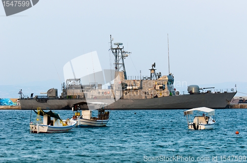 Image of Big battle ship in the dock against blue sky and mountains