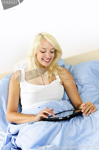 Image of Woman sitting in bed with tablet device