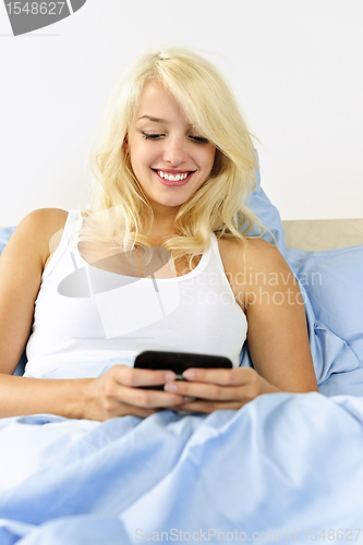 Image of Woman sitting in bed texting