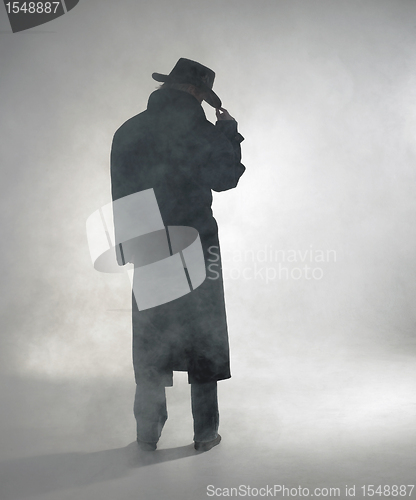 Image of Woman wearing trench coat and standing in fog