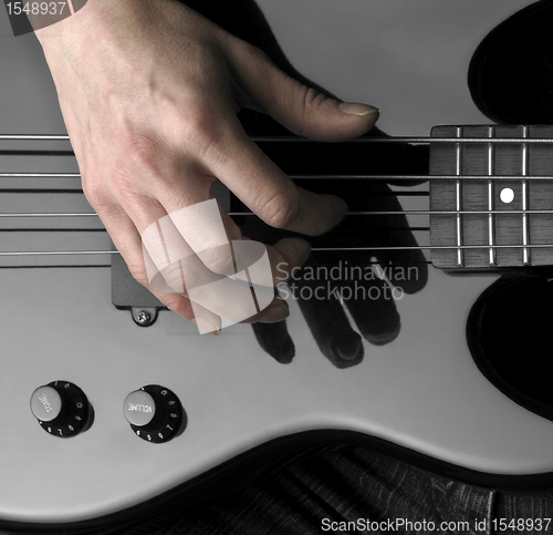 Image of hand on bass guitar