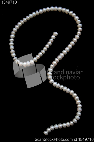 Image of White pearls on the black silk as background 