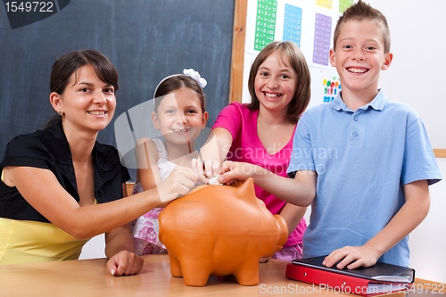 Image of Students and teacher putting coin into piggy bank