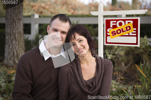 Image of Happy Couple in Front of Sold Real Estate Sign