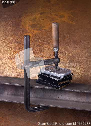 Image of clamp pressing on stack of hard drives