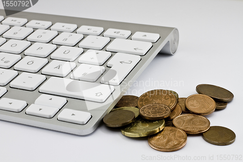 Image of Computer keyboard with white keys and coins