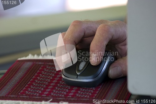 Image of Hand over a Wireless Mouse on a Rug