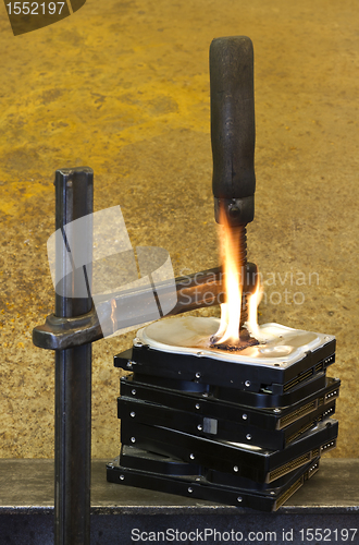 Image of clamp pressing on burning stack of hard drives