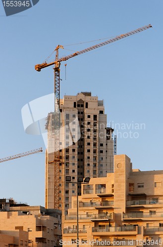 Image of Lifting crane and building under construction at sunset